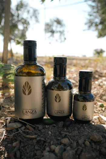 Tre bottiglie di olio extravergine di oliva Kalamata Lanza fotografate nel terreno